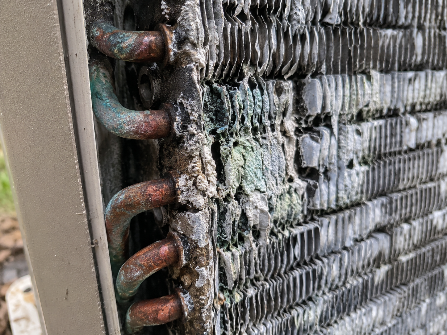 Close-up of corroded AC coils showing white crust and flaking fins